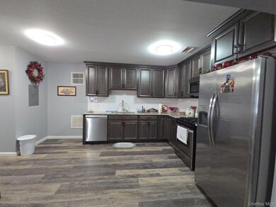 Kitchen with appliances with stainless steel finishes, dark wood finished floors, and dark brown cabinets