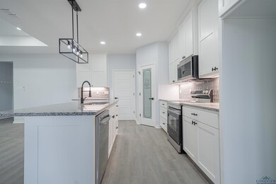Kitchen with white cabinetry, appliances with stai