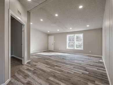 Spare room featuring a textured ceiling and hardwo