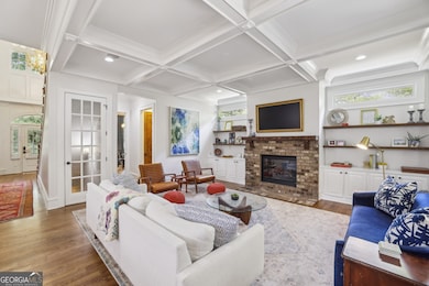 The Living Room is both Stylish and Inviting, featuring a Classic Brick Fireplace, Custom Built-Ins, and Coffered Ceilings.