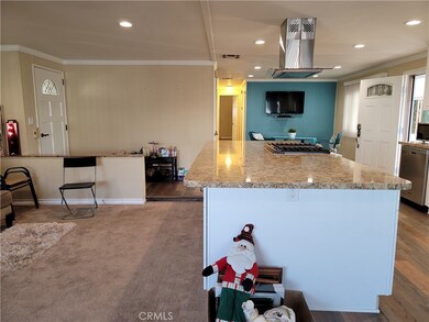 #69 San Rafael living area to kitchen counter island with stove. Recessed lighting, crown molding, floors are carpet and laminate. BE CAREFUL THERE IS A STEP DOWN AT EDGE OF KIT COUNTER.