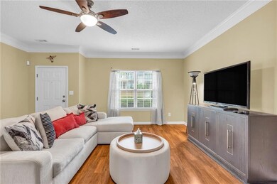 Living room featuring light wood-style flooring, a textured ceiling, a ceiling fan, and crown molding