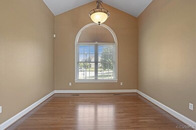 The vaulted living room features wood floors.  This could make a great home office or sitting room.