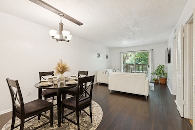 Step into a spacious open-concept dining and living area with warm-toned wood flooring and great natural light. Ideal for entertaining or cozy nights in, this space connects effortlessly to the outdoor balcony.