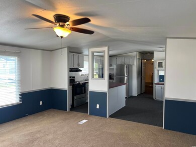 Kitchen with range with electric cooktop, dark colored carpet, lofted ceiling, freestanding refrigerator, and a ceiling fan
