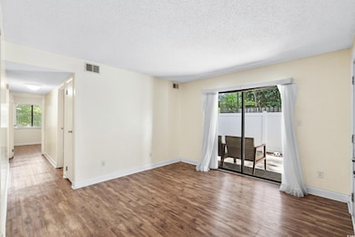Unfurnished room with a textured ceiling and hardw