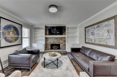 Living room with crown molding, wood finished floors, and built in features