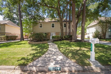 Landscaping in the front lawn features beautiful mature trees and zoysia grass.