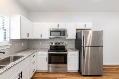 Kitchen with white cabinetry, decorative backsplas