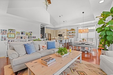 Living room featuring light wood-type flooring, recessed lighting, a raised ceiling, and high vaulted ceiling