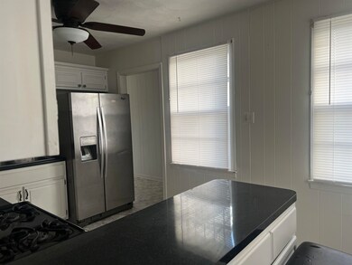 Kitchen with white cabinets, ceiling fan, and stai