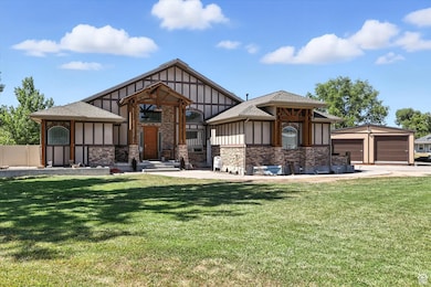 English style home with an outbuilding, board and batten siding, a front yard, a shingled roof, and a detached garage