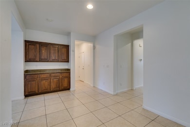 Kitchen with light tile patterned floors, dark stone countertops, recessed lighting, and dark brown cabinets