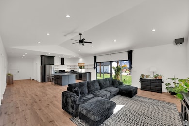 Living room featuring lofted ceiling, light wood finished floors, recessed lighting, and ceiling fan