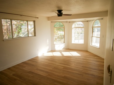 Spare room featuring wood finished floors, a ceiling fan, and a textured ceiling