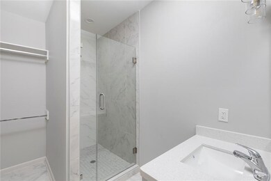 Bathroom featuring a sink, a stall shower, and marble finish floors