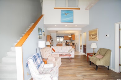 Living room with stairs, a towering ceiling, light wood-type flooring, and recessed lighting