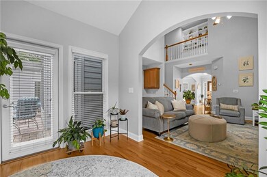 Living area featuring arched walkways, wood finished floors, high vaulted ceiling, and stairs