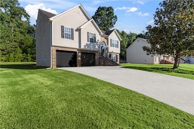 Bi-level home with an attached garage, a front yard, brick siding, and driveway