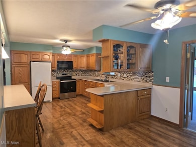 Kitchen featuring open shelves, a ceiling fan, brown cabinets, and freestanding refrigerator