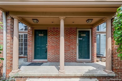 Doorway to property featuring brick siding and covered porch