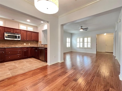 Kitchen with ornamental molding, decorative backsplash, light wood-type flooring, ceiling fan, and open floor plan