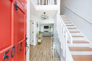 Entrance foyer with stairs, light wood-type flooring, and a chandelier