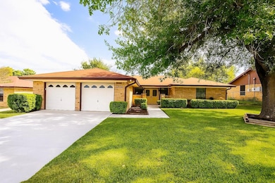 Single story home featuring brick siding, a front lawn, driveway, and an attached garage