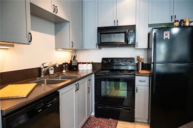 Kitchen with sink, black appliances, and light til
