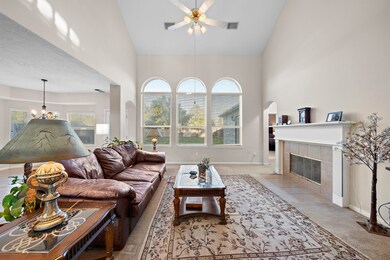 Inviting living area with tall ceilings, arched windows, fireplace, and classic furnishings.