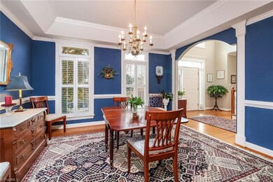 Spacious dining room with hardwood floors, tray ceiling, chair rail and plantation shutters