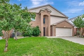 Traditional home with a front yard, concrete driveway, and a garage