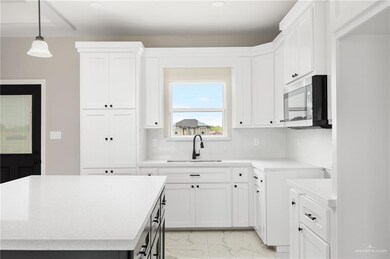 Kitchen featuring white cabinets, light tile floors, tasteful backsplash, and sink