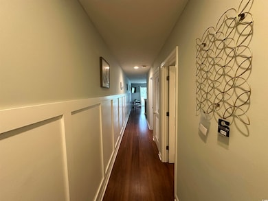 Hall with dark wood finished floors, a wainscoted wall, a decorative wall, and recessed lighting