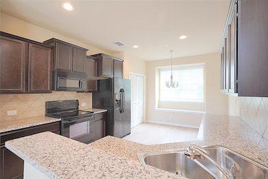 Kitchen featuring black appliances, a chandelier,