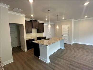 Kitchen with a sink, dark brown cabinetry, ornamental molding, an island with sink, and decorative backsplash
