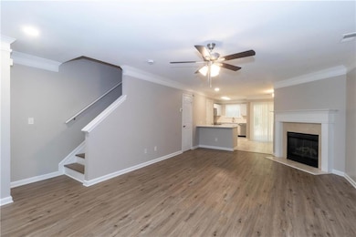 Unfurnished living room featuring ornamental molding, wood finished floors, stairs, a premium fireplace, and ceiling fan