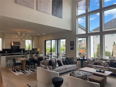 Living room with light wood-type flooring, a towering ceiling, and a chandelier