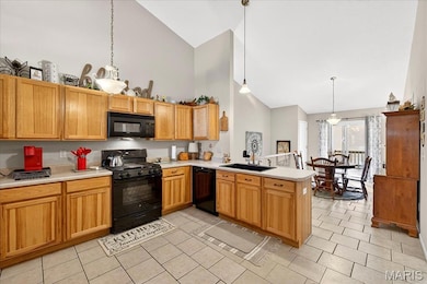 Kitchen with black appliances, high vaulted ceiling, light countertops, decorative light fixtures, and a peninsula