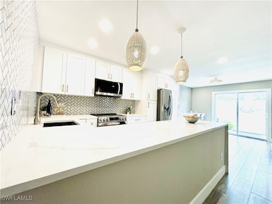 Kitchen featuring stainless steel appliances, light  countertops, decorative backsplash, white cabinetry, and recessed lighting