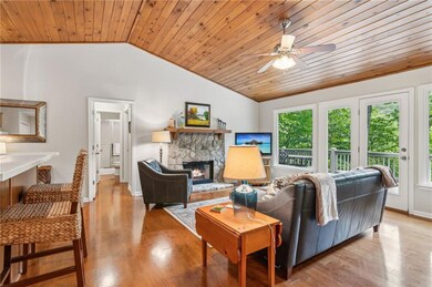 Living area featuring healthy amount of natural light, lofted ceiling, wooden ceiling, ceiling fan, and a stone fireplace