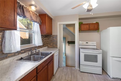Kitchen featuring brown cabinets, white appliances, decorative backsplash, light countertops, and light wood-type flooring
