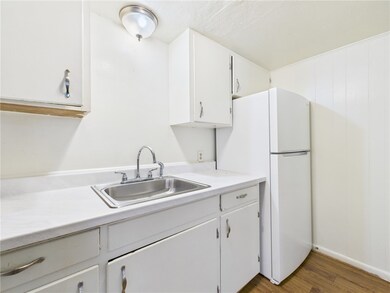 Kitchen featuring light countertops, freestanding refrigerator, dark wood finished floors, and white cabinets