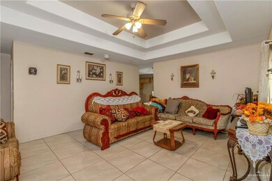 Tiled living room featuring ceiling fan and a tray ceiling