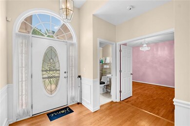Foyer featuring a chandelier, wood finished floors, a wainscoted wall, and a decorative wall