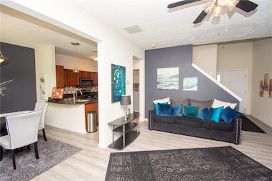 Living room featuring light wood-style flooring, ceiling fan, and a textured ceiling