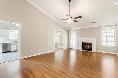 Unfurnished living room featuring vaulted ceiling, a ceiling fan, light wood-style flooring, healthy amount of natural light, and a premium fireplace