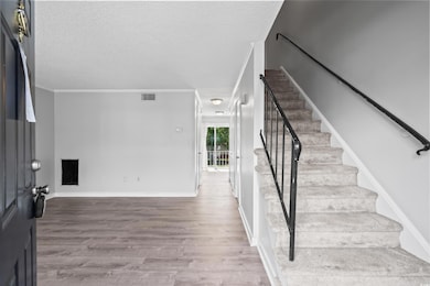 Stairway with wood finished floors, a textured ceiling, and crown molding
