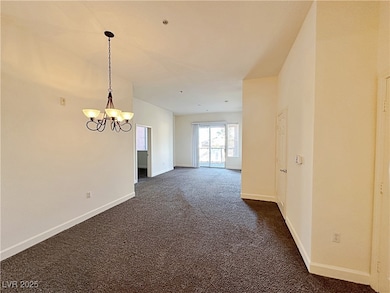 Empty room featuring a chandelier, dark colored ca