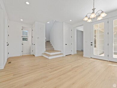 Unfurnished living room featuring light wood-style flooring, recessed lighting, a chandelier, and stairs
